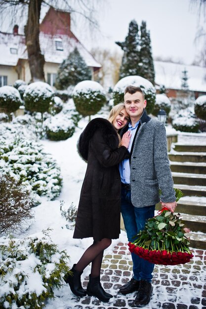 Loving couple in love at winter day with large bouquet of 101 roses