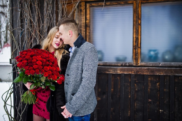 Loving couple in love at winter day with large bouquet of 101 roses