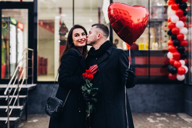 Loving couple posing on street with balloon