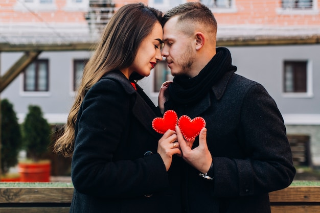 Foto gratuita coppia di innamorati in posa con cuori rossi