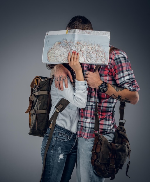 Free photo loving couple ready to travel with backpacks and a map. a man kissing a woman.