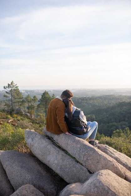 秋のハイキングの後に休んでいる愛情のあるカップル。ピーク時に座って、肩に寄りかかってハイキング弾薬とカジュアルな服装の男女。自然、活動、趣味の概念