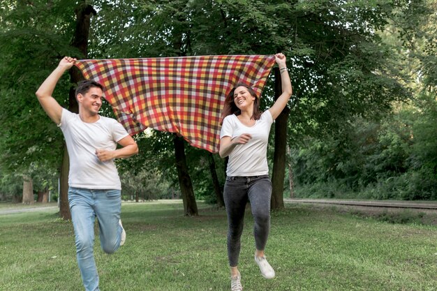 Loving couple running with a blanket in nature