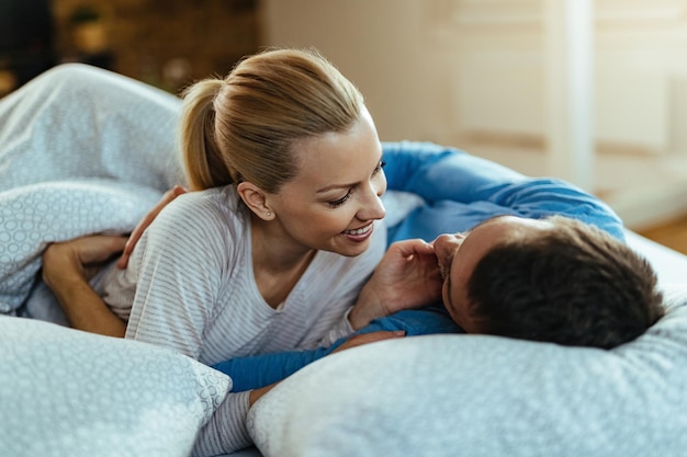 Loving couple showing affection while relaxing in the morning in their bedroom.