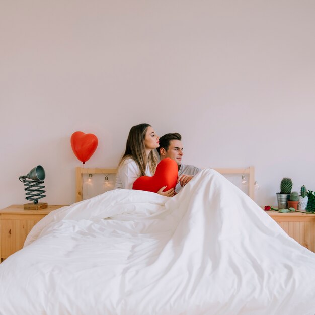 Loving couple sitting on bed with heart