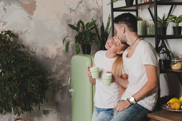 Loving couple standing in kitchen holding cup of coffee