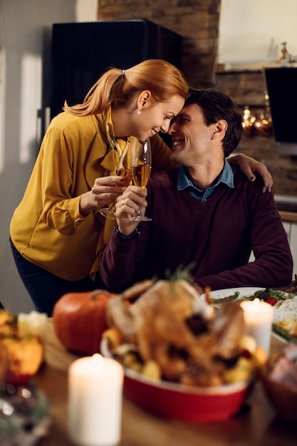 loving couple toasting with champagne on thanksgiving in dining room