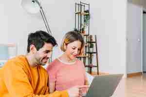 Free photo loving couple using laptop on floor