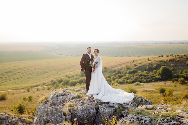 Loving couple wedding newlyweds outside at sunset in beautiful summer day