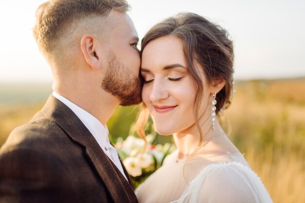 Loving couple wedding newlyweds outside at sunset in beautiful summer day