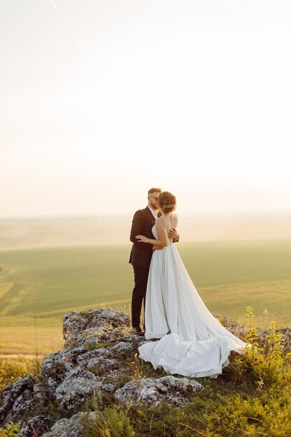 Loving couple wedding newlyweds outside at sunset in beautiful summer day