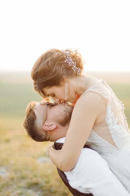 Loving couple wedding newlyweds outside at sunset in beautiful summer day