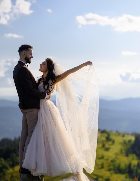 Влюбленная пара в свадебных нарядах позирует на природе в горах