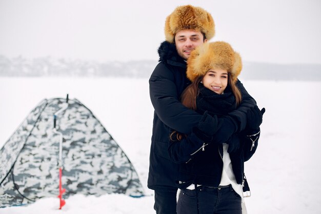 氷の上に冬服を着て立っているカップルを愛する