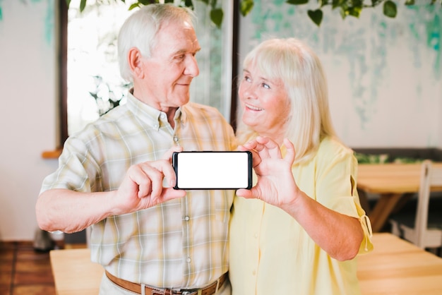 Free photo loving elderly couple showing smartphone to camera