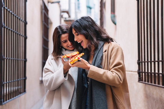 Free photo loving excited women enjoying pizzas together