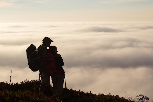 Loving family hiking on summer. Man and woman in casual clothes and with ammunition hugging. Hobby, active lifestyle concept