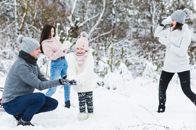 田園地帯で雪だるまをする家族を愛する