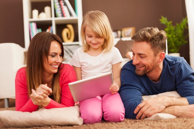 Любящая семья с помощью цифрового планшета на ковре