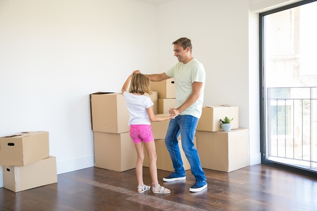 Loving father having fun and dancing with preschooler daughter in new home