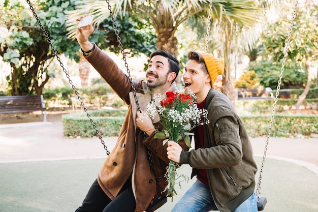 Loving men taking selfie with bouquet