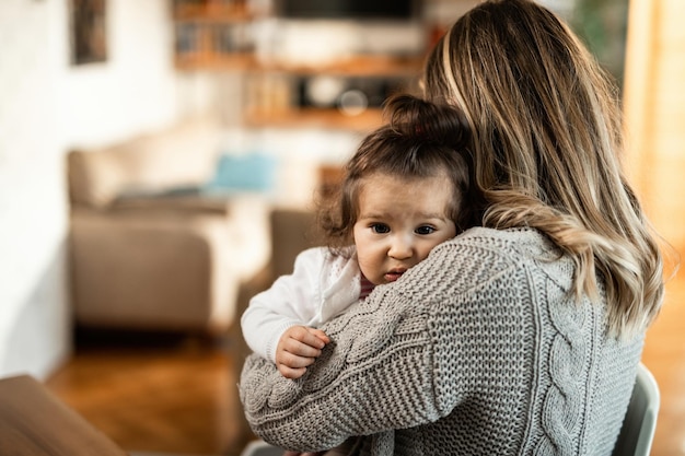 Loving mother embracing her small daughter at home Focus in on daughter