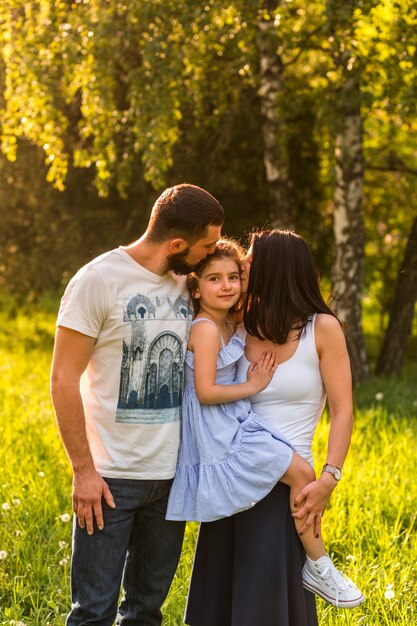 Loving parents kissing their daughter in park