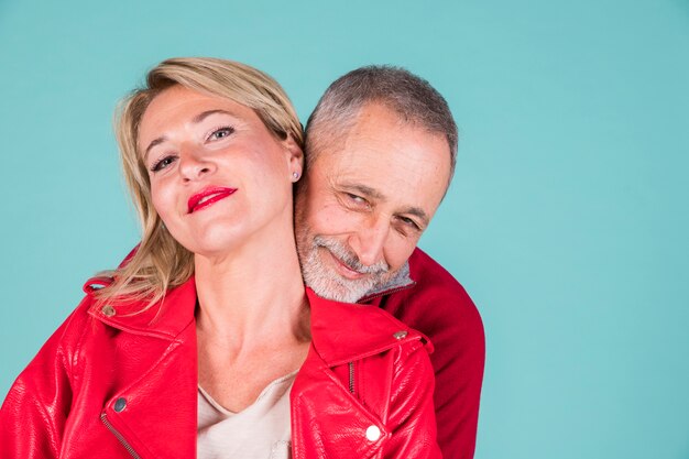 Loving portrait of smiling mature couple against turquoise backdrop