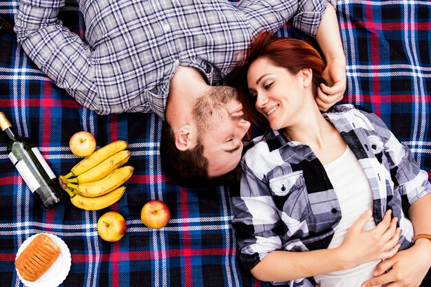 彼女の夫が毛布にたくさんの果物を置き、愛する女性