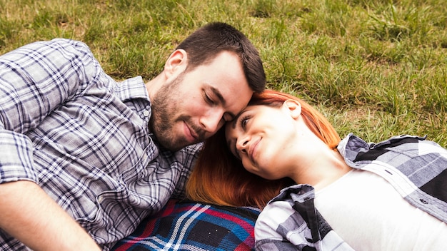 Free photo loving young couple lying on blanket over green grass