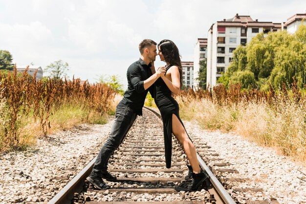 Loving young couple posing face to face on the railroad