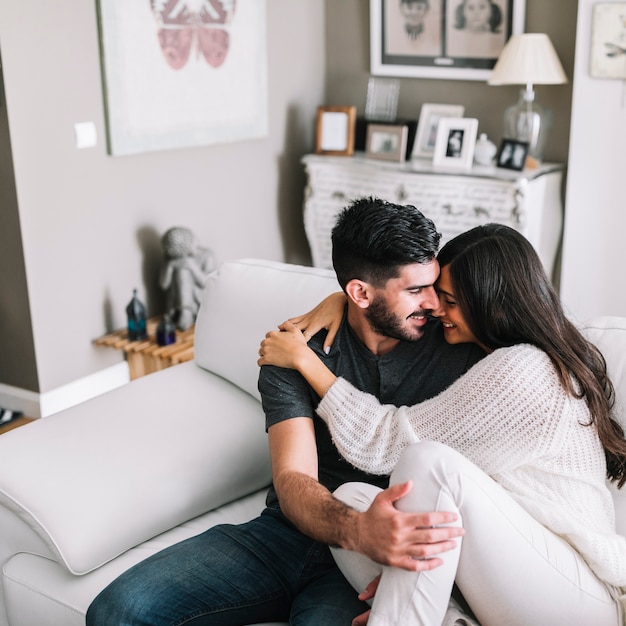 Loving young couple sitting on sofa at home