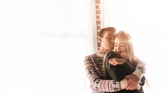 Loving young couple standing in front of window