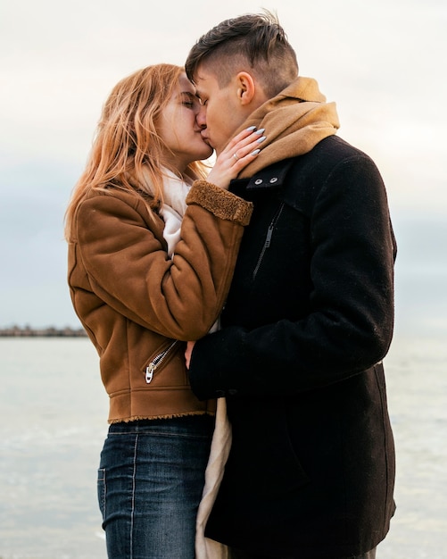 Loving young couple in winter by the beach kissing