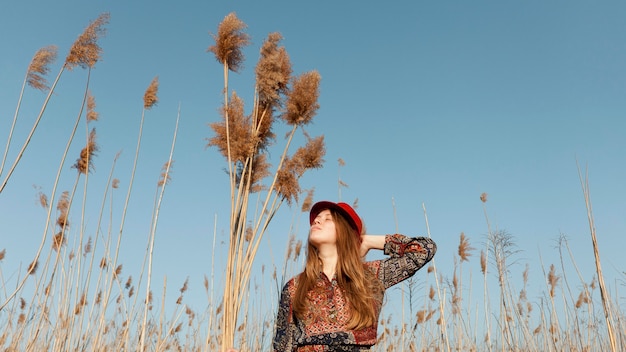 Low angle of beautiful bohemian woman posing in nature