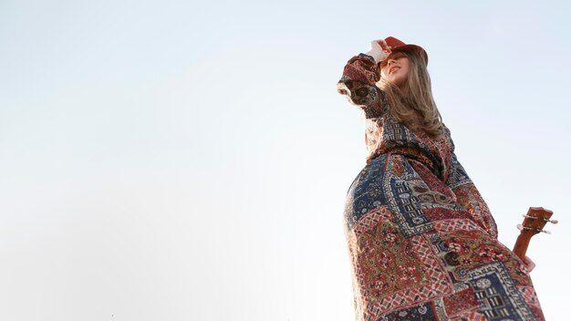 Low angle of bohemian woman with copy space and ukulele