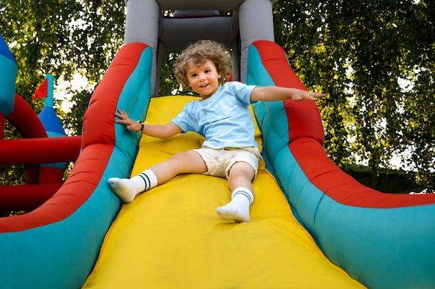 Free photo low angle boy playing in bounce house