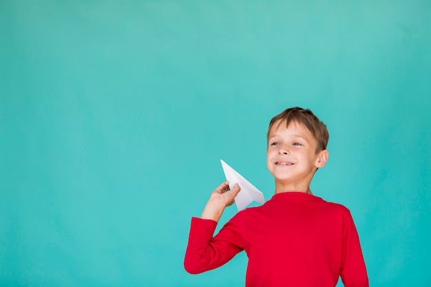 Low angle boy throwing a paper airplane with copy space