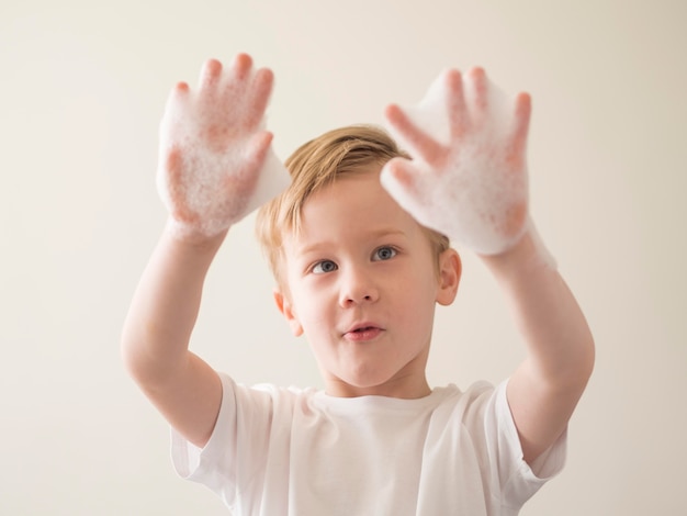 Free photo low angle boy with foam on hands