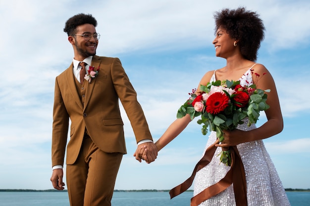 Free photo low angle bride and groom posing outdoors