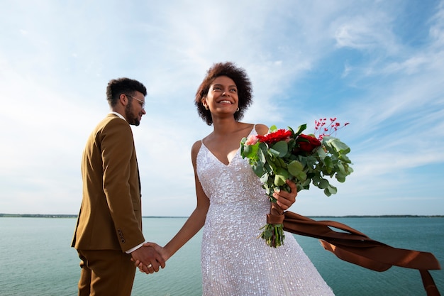 Foto gratuita la sposa e lo sposo in basso angolo posano all'aperto