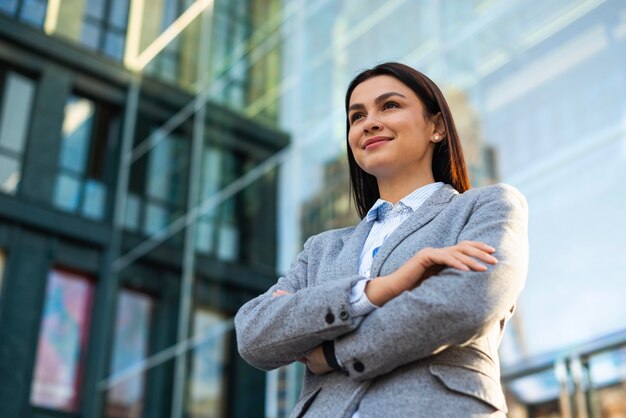 Low angle of businesswoman posing with arms crossed in the city