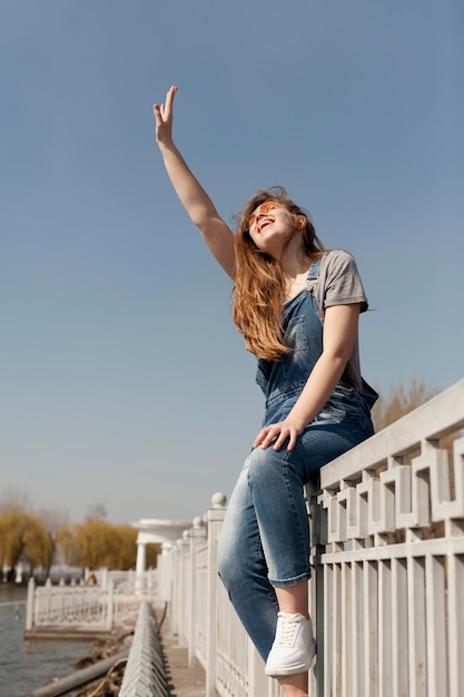 Free photo low angle of of carefree woman posing on railing