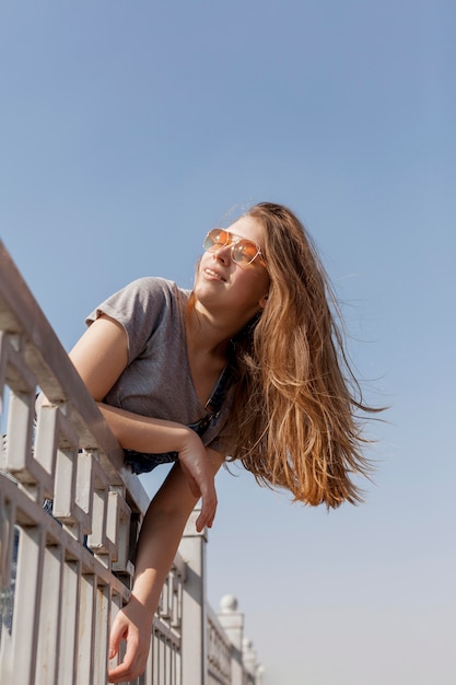 Free photo low angle of of carefree woman posing with sunglasses