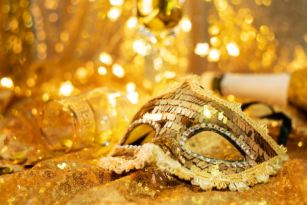 Free photo low angle of a carnival mask and a glass with coins