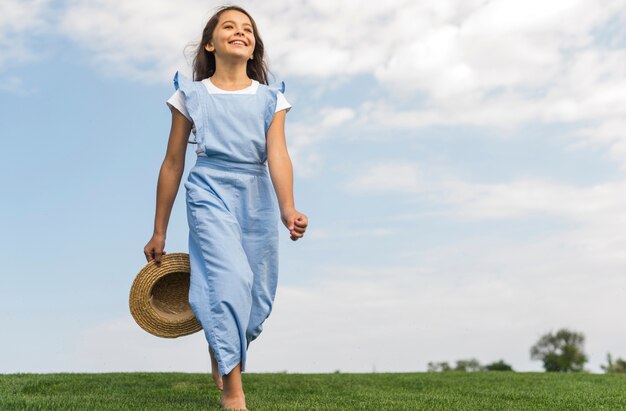 Low angle cheerful girl walking barefoot on grass