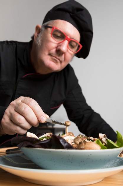 Free photo low angle chef cooking salad with mushrooms