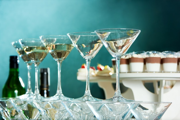 ローアングルは、レストランのディナーウェアガラス製品アルコールお祝いお祝いドリンク飲料気分でパーティーテーブルの上のマティーニグラスのショットを閉じます。