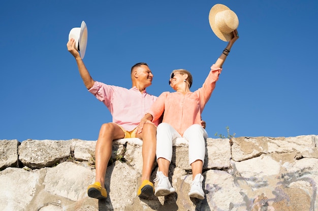 Free photo low angle couple sitting on cliff