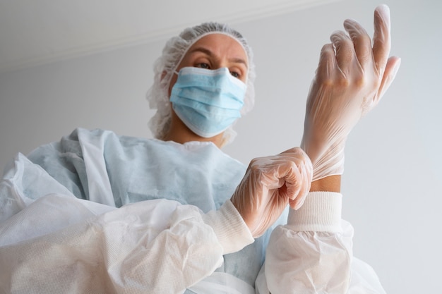 Free photo low angle doctor putting on glove